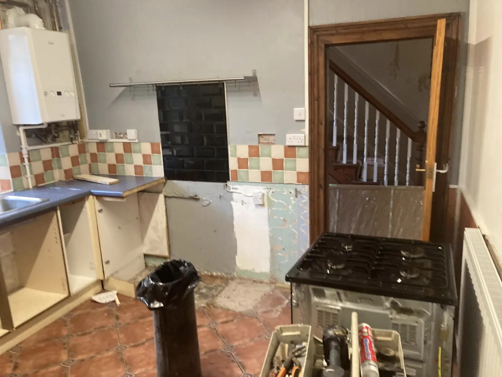 Kitchen before renovation with removed cabinetry and dated finishes